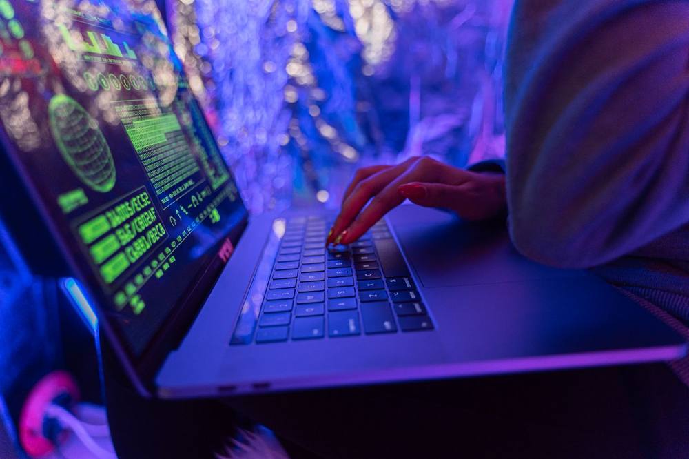 Tangan seseorang mengetik pada laptop dengan latar keamanan siber